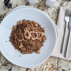 Buckwheat with porcini mushrooms served on white plate on marble table