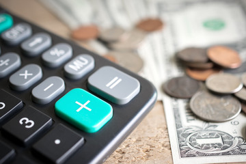 Closeup of calculator plus green button with money on wood board economic growth concept.