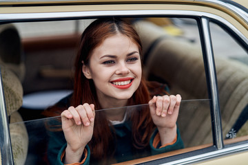 happy woman looks at the street through the window in the car