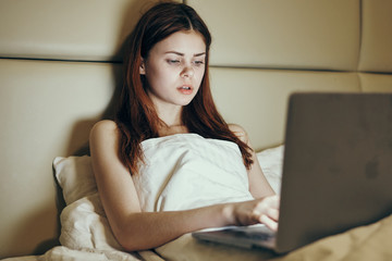 woman lies in bed with laptop