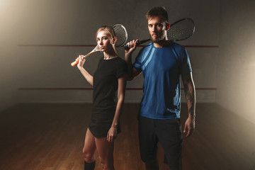 Male and female squash game players with rackets