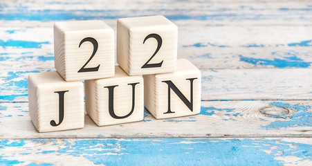June 22nd. Wooden cubes with date of 22 June on old blue wooden background.