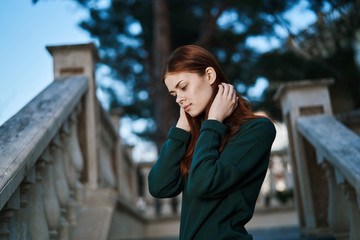 Fototapeta premium woman in green sweater, trees and building in the background