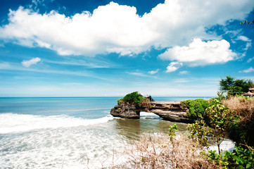 Pura Tanah Lot. Unique hindu temple on a rock in the sea, Bali, Indonesia. dramatic sky with clouds and ocean with waves.