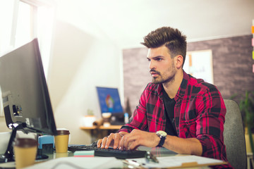 Obraz na płótnie Canvas Handsome caucasian man at work desk facing flat screen computer screen in office