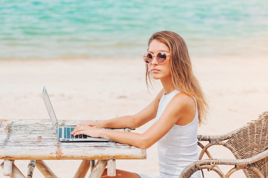 Young sexy woman using laptop on the beach. Freelance work