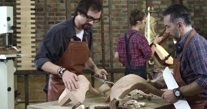 Wooden Furniture Restoration Workshop/An average day at a family woodworking shop. Young man polishes a cabrioli leg before finishing coating