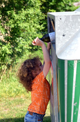 Kind wirft Flasche in eine Tonne