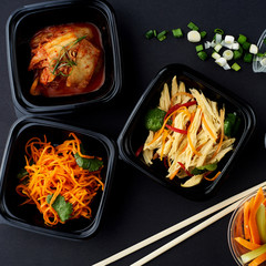 Korean cuisine. Set of salads on black background. Asparagus, korean carrot, kaktugi, fresh vegetable sticks and green onion.