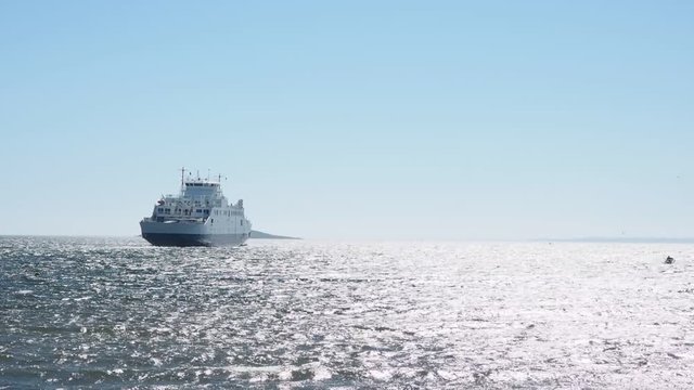 Little ferry crossing over shimmering water in gale wind with clear blue sky