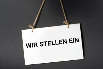 Ein weisses Schild mit dem Slogan Wir stellen ein