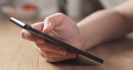 female teen girl using smartphone sitting at the table