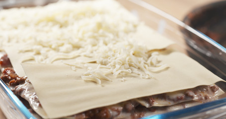 preparing traditional italian lasagna adding cheese