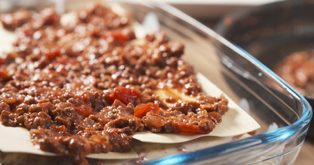 preparing traditional italian lasagna adding bolognese sauce