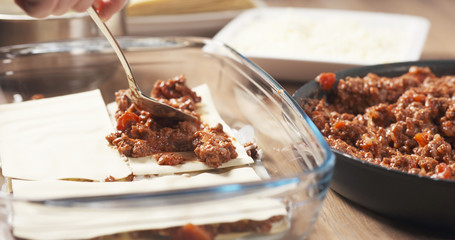 preparing traditional italian lasagna adding bolognese sauce