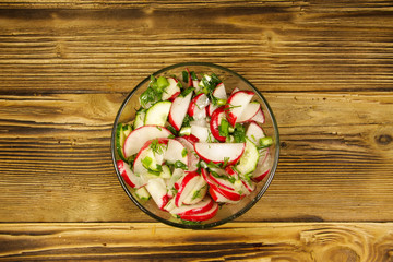 Radish salad in glass bowl on wooden table