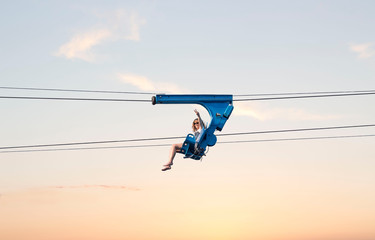 Fototapeta na wymiar horizontal image of a young woman taking an air ride on a zip line in the early evening sun setting.