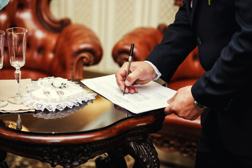 Wedding ceremony.Man signing marriage contract, closeup, Groom signing marriage license or wedding contract,The groom signs the marriage registration documents.