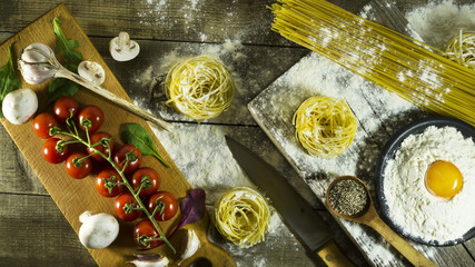 Italian pasta, flour and raw egg on a rustic wooden table.