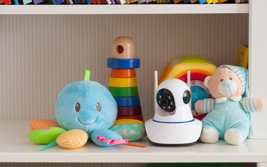 IP camera on the shelf with toys, serving as a baby monitor