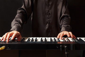 Musician playing the electronic synth on a black background