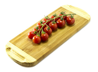 Mature Cherry tomatoes on a cutting board on a white background.