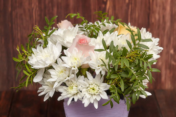 Bouquet of white flowers in wooden basket on wooden background