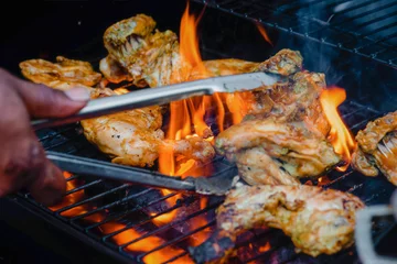 Keuken spatwand met foto Chef cooking jerk barbecue BBQ chicken on the grill hand turning food © Altin Osmanaj