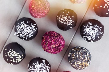 Various fitness raw bites, chocolate truffles, rose petals. Food photography on gray background