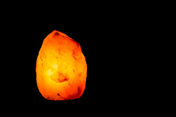 Himalayan salt lamp lit on black background