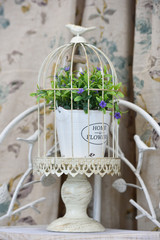 Decorative cage with flowers inside and a figure of a bird