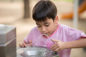 Little asian boy drinking water in the public park - 154675423