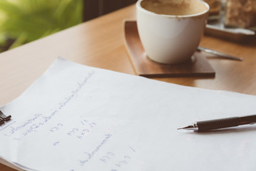 The black pencil is located on a paper that takes mathematics. And the coffee is gone in the coffee shop.