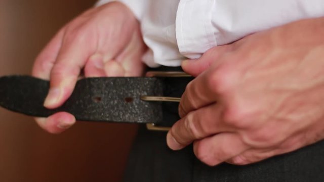 Man trying to button his belt