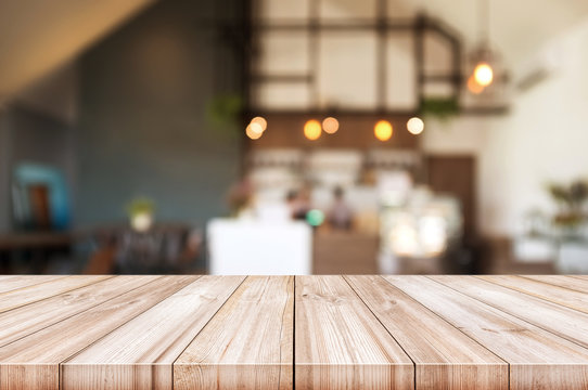 Empty wooden table top with blurred coffee shop interior background.
