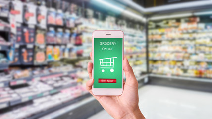 woman hand  holding mobile with grocery online on screen with blur supermarket background