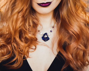 close-up portrait of young beautiful red-haired girl in the image of a Gothic witch on Halloween on...