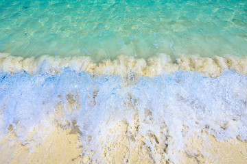 Soft wave of the tropical sea on the sandy beach. Natural summer background with copy space for background texture