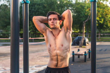 Fitnes man posing on street fitness station showing his muscular body