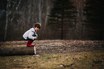 Boy crouching on a log getting ready to jump