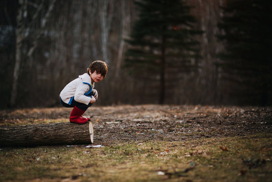 Boy crouching on a log getting ready to jump