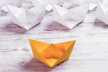 Business leadership concept with white and color paper boats on 