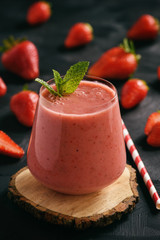 Healthy food - strawberry smoothie in glass on black background.