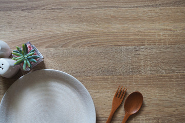 Brown wooden texture for background and there is a blank white plate for the text placed in the bottom corner. copy space