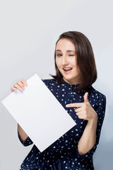 Naklejka premium beautiful brunette girl shows a finger on a clean white paper, winks with a smile, happiness, joy, emotions