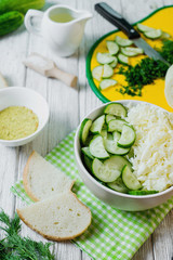  vegetarian Healthy food, light, low calorie fitness salad of fresh cucumbers, cabbage and dill with olive or sunflower oil, spices and salt on a light wooden background 