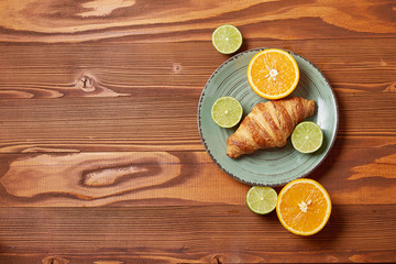 Fototapeta na wymiar Food plate of Citrus mix and croissant on wooden background