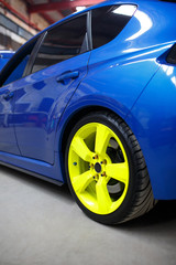 Blue car with green alloy wheel indoor