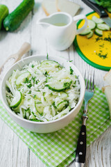  vegetarian Healthy food, light, low calorie fitness salad of fresh cucumbers, cabbage and dill with olive or sunflower oil, spices and salt on a light wooden background 