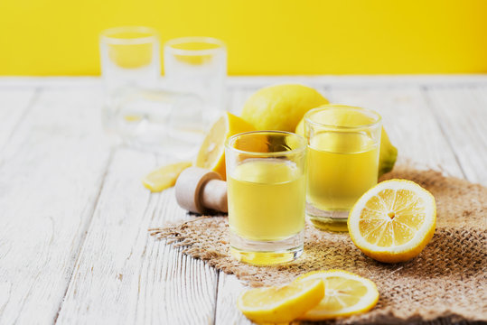 Alcoholic drink, Italian liqueur limoncello in wine-glasses with lemons on a wooden background